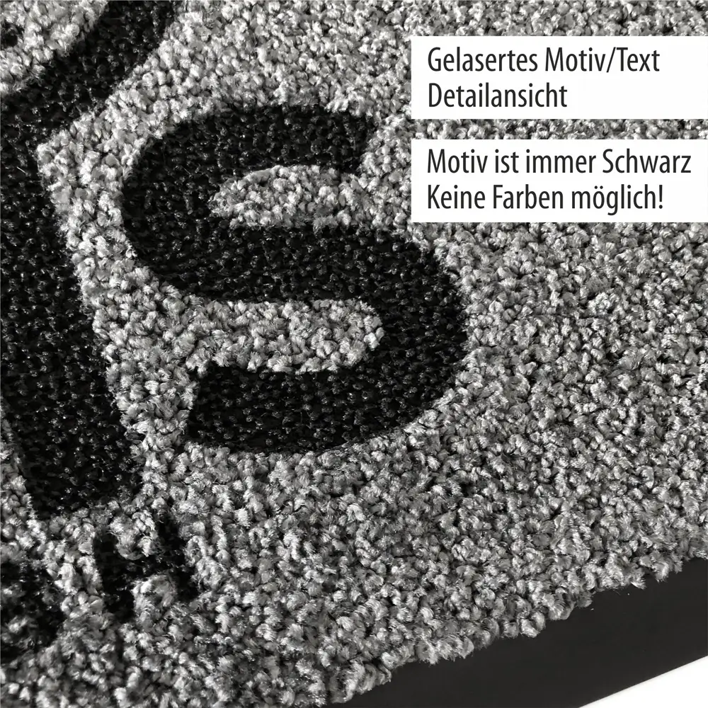 Nahaufnahme eines schwarzen gelaserten Motivs auf einem grauen Teppich. Der Hinweis besagt, dass das Motiv immer schwarz und keine anderen Farben möglich sind.